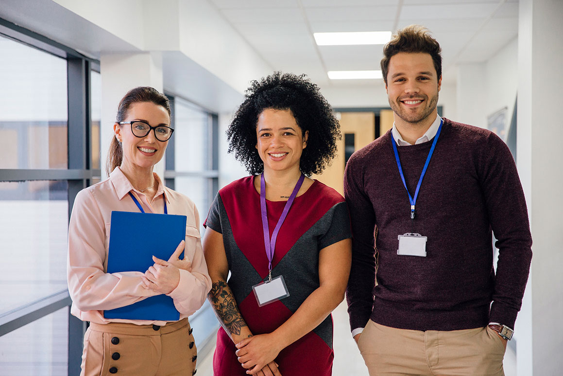 Two females and a male senior employees standing in a school coridor
