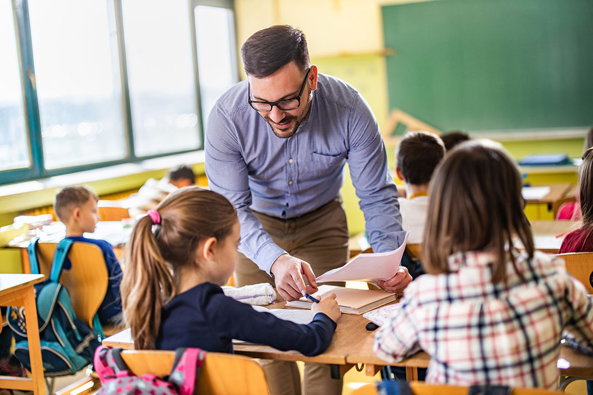 Male teacher helping primary school students